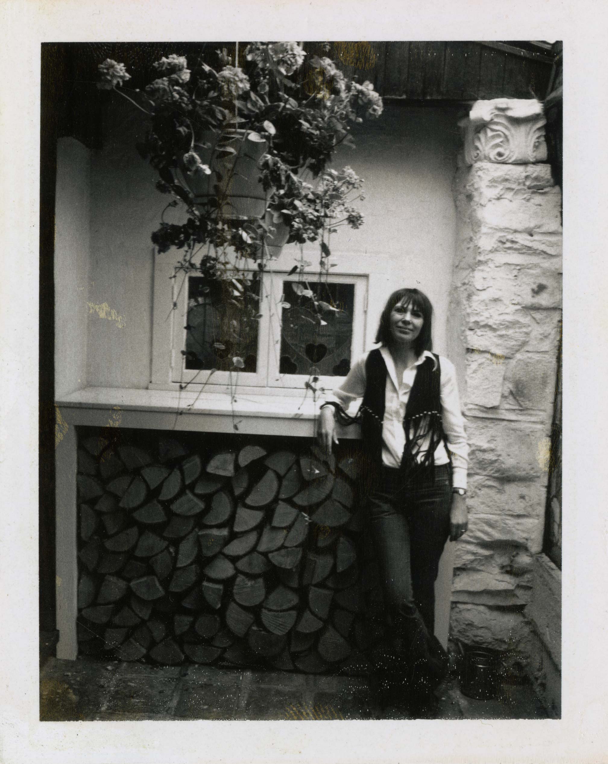 woman in fringe vest against a stone wall